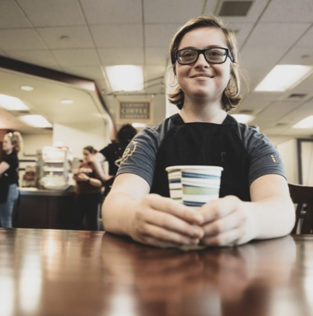 LEAP participant with glasses sitting at a table with a cup of coffee.