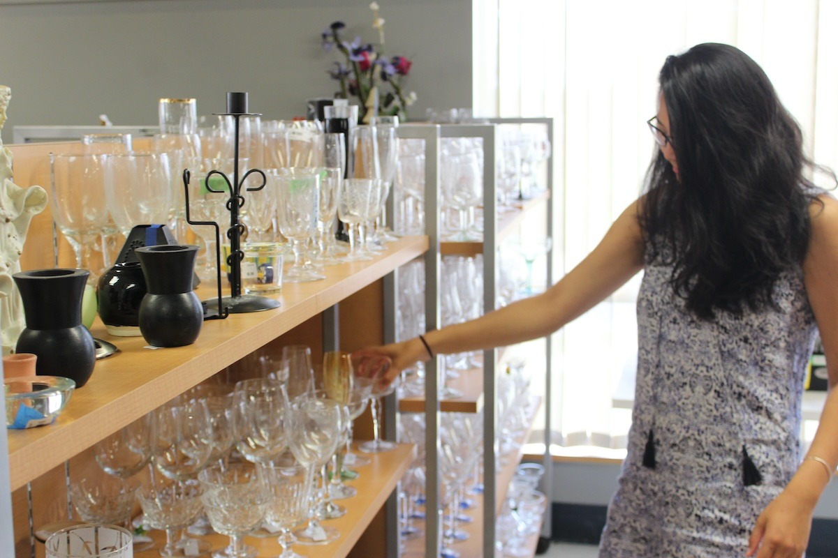 A customer examines glassware on shelves at ReSOURCE, a Vermont-based non-profit offering essential goods to alleviate poverty. The program empowers low-income families by providing necessary household items through a robust network of partner agencies.