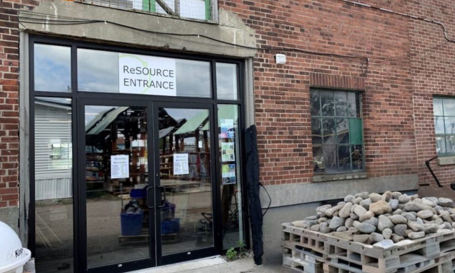 Entrance of ReSOURCE Burlington, set against a red brick building, inviting eco-conscious shoppers to explore its curated collection of reused goods.