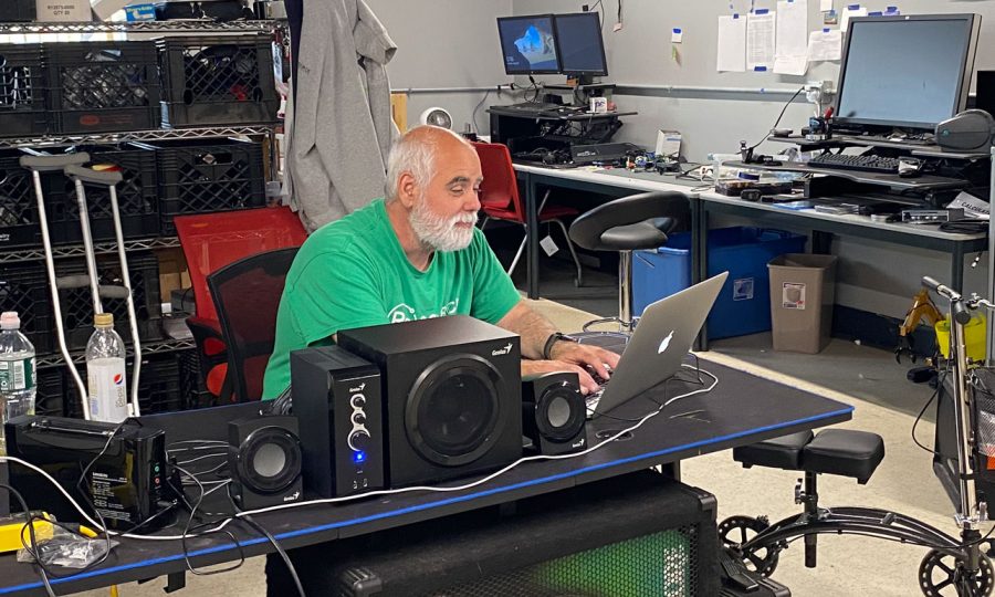 Dedicated technician at ReSOURCE Vermont's repair shop providing computer sales and services, surrounded by electronics and repair tools, accessible to all Vermonters.